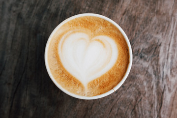 Close up of fresh delicious cappuccino coffee with beautiful latte art in the shape of heart on dark wooden background. 