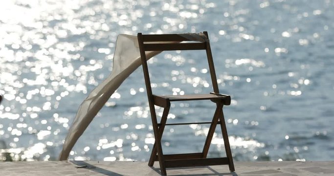 Symbolism lonely chair at the pier, shawl develops from the wind, 