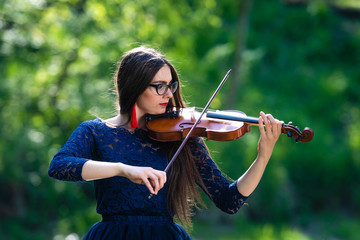 Young woman playing the violin at park. Shallow depth of field - image