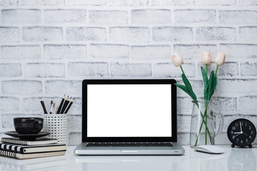 Laptop mock up and black and white supplies on brick wall. Creative workspace.