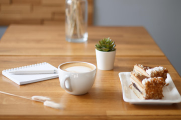 coffee in a Cup with a heart on a wooden table with a notebook and a tablet in a cafe with a flower work in the morning