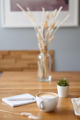 coffee in a Cup with a heart on a wooden table with a notebook and a tablet in a cafe with a flower work in the morning