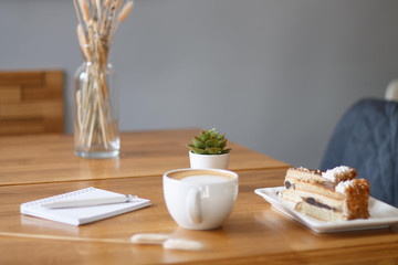 coffee in a Cup with a heart on a wooden table with a notebook and a tablet in a cafe with a flower work in the morning
