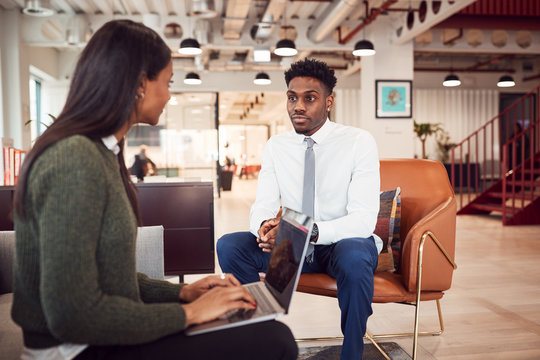 Businesswoman Interviewing Male Job Candidate In Seating Area Of Modern Office