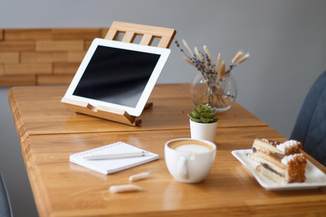 coffee in a Cup on a wooden table with a notebook and a tablet in the cafe work in the morning