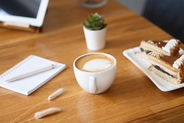 coffee in a Cup on a wooden table with a notebook and a tablet in the cafe work in the morning