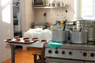 Fototapeta na wymiar At the kitchen: gas-stoves, dishes, cooking utensils set on kitchen desk 