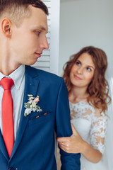 Beautiful bride in white dress and groom in suit, posing in white Studio interior, wedding