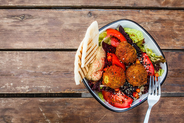 Israeli street food. Falafel salad with hummus, beetroot and vegetables in bowl on wooden...