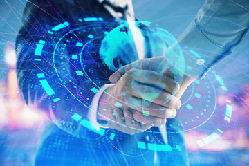 Double exposure of world map on cityscape background with two businessmen handshake. Concept of international business