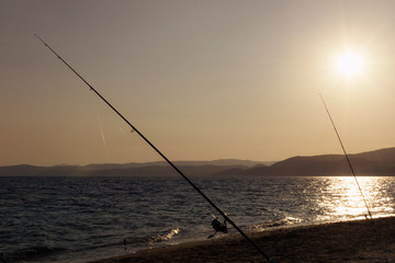 Fishing rods on beach shore at sunset