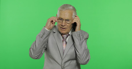 Handsome elderly businessman talks on a smartphone. Old man in suit