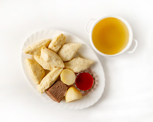 Dish with Avar khinkal and a portion of beef broth on a white background top view