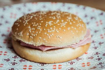 Hamburger jambon fromage dans une assiette en céramique décorée