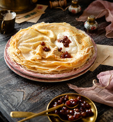 Homemade stack of thin crepes with sour cream and red jam on vintage pink plates