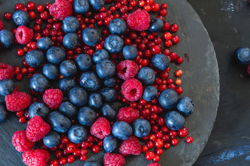 Detail of raspberries, blueberries and redcurrants on a slate dish, top view