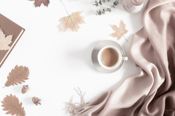 Autumn home cozy composition. Dried autumn leaves, cup of coffee, book, scarf, flowers on white background. Fall background. Flat lay, top view, copy space