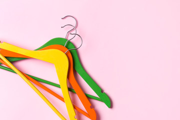 Creative flat lay multicolor wooden hangers at pink pastel background with copy space minimalist style.