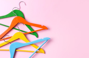 Creative flat lay multicolor wooden hangers at pink pastel background with copy space minimalist style.
