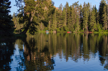 Small Canadian pond with big reflections of trees and canoes