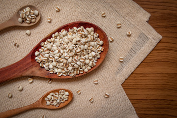 Picture of millet in a wooden spoon that is cereal and food on a brown tablecloth, wood grain, suitable for food advertising,top viwe
