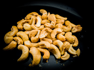 Fried roasted cashew nuts on black plate