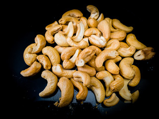Fried roasted cashew nuts on black plate