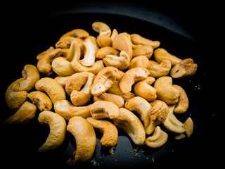 Fried roasted cashew nuts on black plate