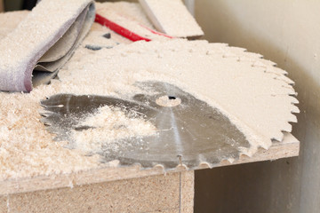 Close-up of a heap of fine carpentry dust near a working circular saw and on disks for a circular saw, selective focus
