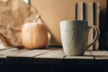 Pumpkin, tea and autumn leaves on the background. Autumn still life with pumpkin, candle and cup of tea on the wooden table. Thanksgiving, autumn season. Copy spase