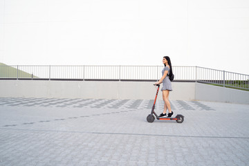 Pretty long hair girl driving e scooter in the city , whole body shot , copy space,