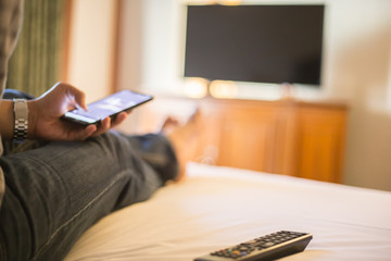 Obraz premium Man using mobile phone in bed room, selective focus and blur background