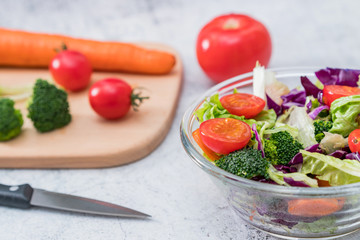 A bowl of vegetable salad and various vegetables on a cutting board