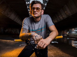 Tattooed hipster man on BMX bike posing 