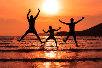 Fototapeta na wymiar Silhouette young boys different action jumping on the sand beach and sunset seascape background.Happy and funny time together concept. K