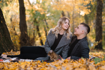 Beautiful young couple resting in autumn park. autumn concept. Loving couple resting with their cat.
