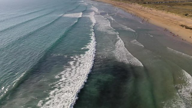 ocean waves sandy beach with people bathing in the water view from drone Lanzada beach Galicia Spain 4k video