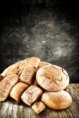 Rolls and braed on wooden table top and black wall.