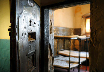 Fototapeta na wymiar In the prison. Metal door opened, part of a cell with bunks and mattresses visible, bars on a window