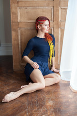 beautiful girl girl with an exotic hairstyle gracefully sits on the floor, stretching her legs