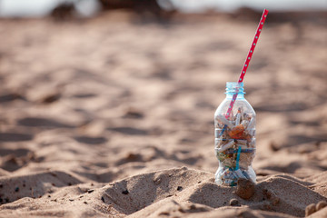 Cocktail with garbage and straw on clean beach. Plastic ocean pollution, environmental crisis. Say no plastic. Single-use plastic waste, world ocean day, eco concept