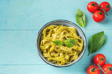 Popular Italian pasta with pesto sauce, close-up on a blue wooden background. Top view, copy space. Vegetarian food.