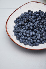 plate with delicious blueberries on white wooden table