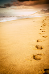Footprint on the beach with nobody there - concept of travel and adventure lifestyle - wild mountains and scenic place in backgrund - summer holiday vacation concept