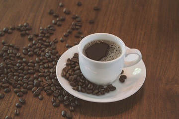 Hot coffee cup with coffee beans on wood table