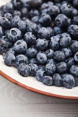 close up view of plate with delicious blueberries on white wooden table