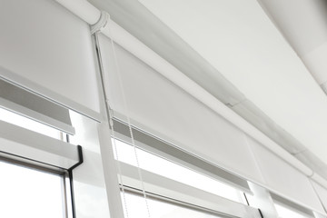 Obraz premium Modern window with white roller blinds indoors