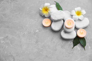 Composition with spa stones, flowers and candles on grey marble background. Space for text