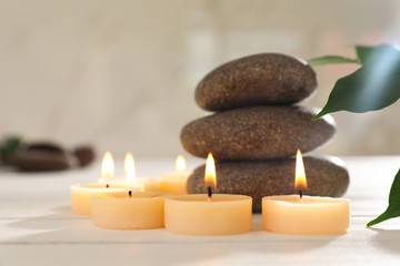 Composition with spa stones and candles on white wooden table