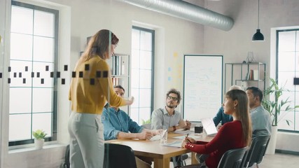In the Meeting Room Young and Beautiful Female Junior Associate Makes a Speech / Report to a Board of Directors Member who are Sitting at the Conference Table. Modern Startup in the Stylish Office